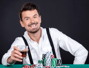 A high limit gambler with a lot of casino chips smiling with a drink in hand